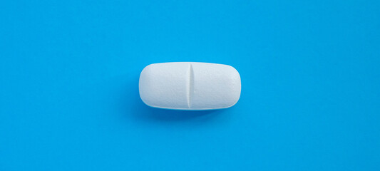 White medicine pill tablet on blue background