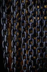 Heavy iron chain. Background of iron chains hanging in even rows on a golden background. Side view.