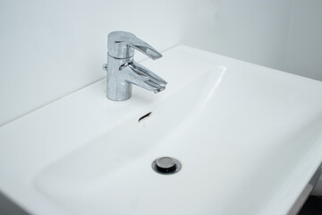 Close up of a bathroom faucet with limescale stains and dirty sink
