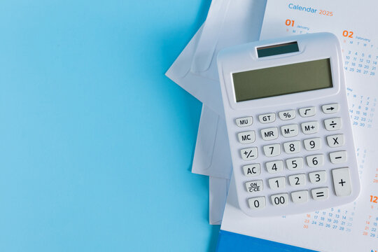 close up top view on calculator with pencil and calendar on blue background for money expense and debt management monthly concept