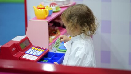 Little girl playing cashier with toy cash register