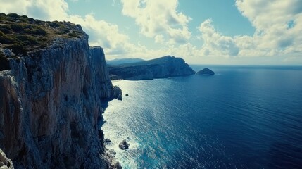 Majestic coastal cliffs meet deep blue sea under a bright cloudy sky panorama view