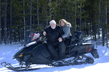 Senior married couple take a break from snowmobiling.