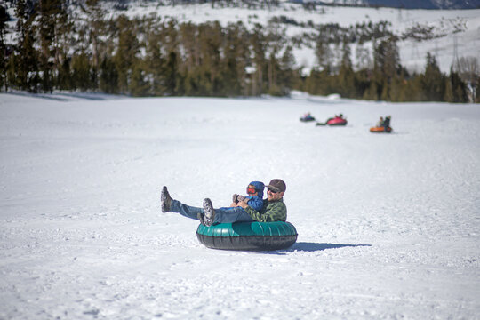 Father and son snow tube down a colorado hill.