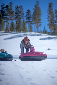 Mom pushes toddler 5yo daughter downhill snow tubing.