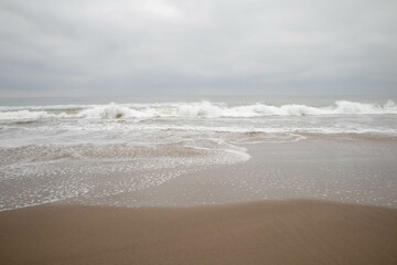 Stormy Ventura California beach, foaming crashing waves, gray sky