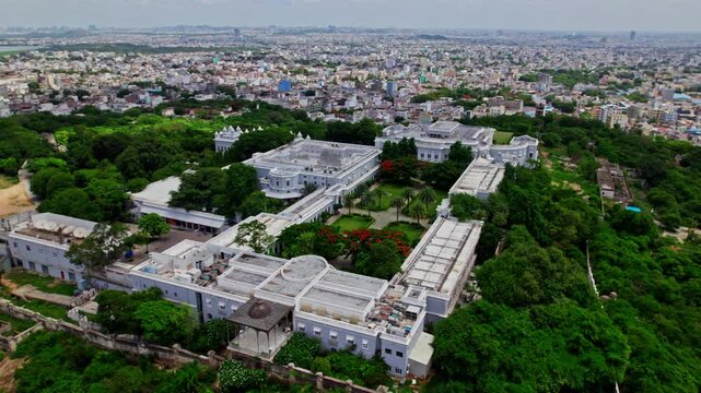 top down drone view of falaknuma palace with trees and crowded residence buildings at engine bowli, falaknuma, hyderabad, telangana, india. day time, semi orbit, drone shot, 4k.
