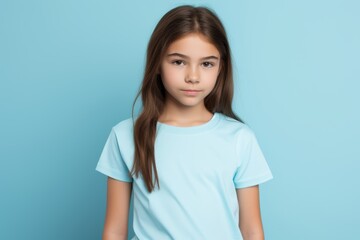 A young girl is wearing a blue shirt and looking at the camera