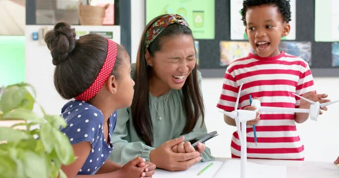 In school, teacher and students discussing wind turbine model in classroom