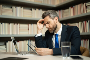 Tired man having a terrible headache. Exhausted man feeling unhealthy, upset about headache illness. Stressed middle-aged man having headache. Migraine and headache concept.