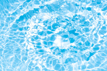 Blue water with ripples on the surface. Defocus blurred transparent blue colored clear calm water surface texture with splashes and bubbles. Water waves with shining pattern texture background.