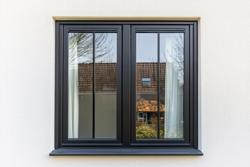Exterior view of modern double window showcasing reflection of a suburban house and garden, bright daylight highlighting the clean lines and structure