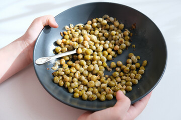 Child holding plate with fried green peas on plate, vegetarian food, nut