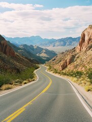 Fototapeta premium A long, curvy road winds through a desert landscape. The road is lined with trees and the mountains in the background create a sense of depth and vastness. The yellow lines on the road guide drivers