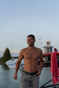 A young man with a naked torso near a yacht