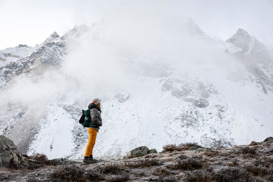 Female wears cold weather gear and headlamp while trekking Nepal