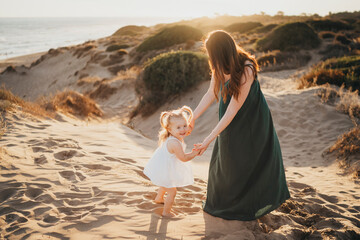 Mother and toddler daughter dancing at beach sunset Spain