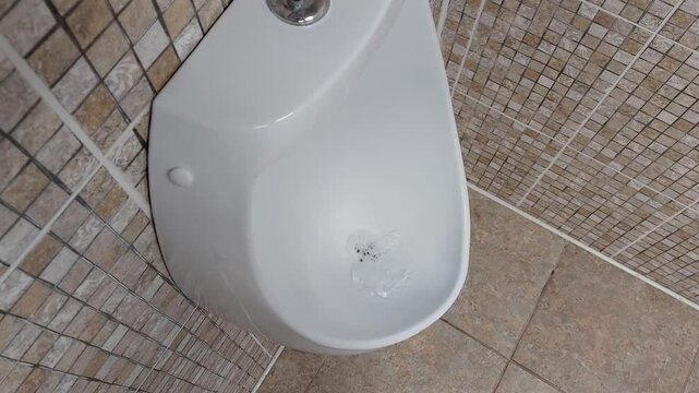 Wall-mounted men's urinal in a public toilet. The concept of cleanliness and hygiene in public toilets. Copy space for text, enuresis