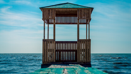 wooden arbor on the background of the sea and blue sky with clouds
