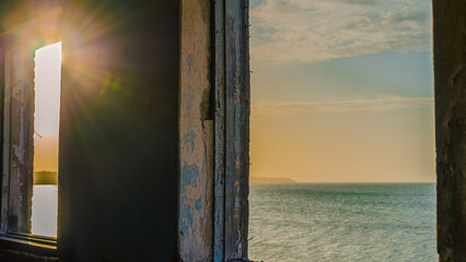 sea landscape and sun in the window of the destroyed room