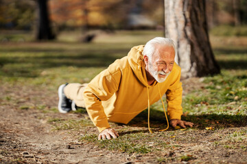 A fit healthy active senior man in shape doing pushups in nature on his fitness day.