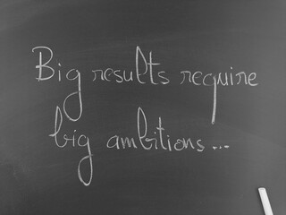 Big results require big ambitions handwritten on a chalkboard in monochrome
