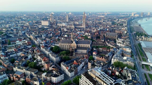 High-altitude drone footage of Antwerp, Belgium, reveals a panoramic cityscape under a clear morning sky, showcasing the historic city center with its iconic cathedral spire prominently