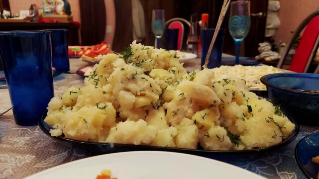 Hot mashed potatoes with dill on a festive home table with dishes and serving, close-up