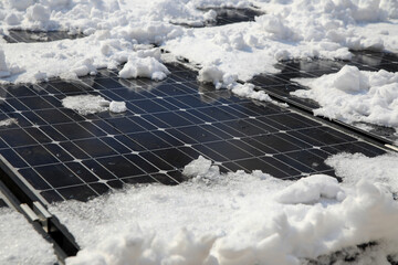 Sun is shining on solar panels in winter and melting away the snow coverage and starting to create...