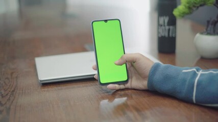 Man holding smartphone with green screen for copy space, making tap, swipes and scrolling gestures. Chroma key mock up for advertising, social networks.