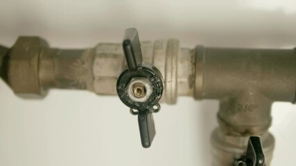 A man's hand closes and then opens a ball valve that regulates the flow of water in a home's plumbing system. Closeup. Macro. Shot in motion. Shallow depth of field