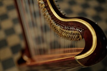 Close up on tuning pins and levers of antique harp with wooden curved frame captured against checkered floor indoors, copy space