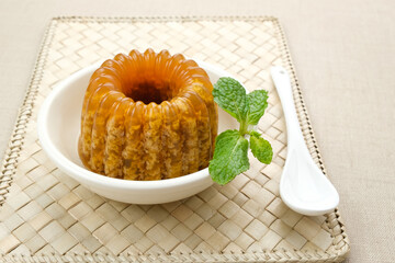 Puding Lumut Gula Merah, moss textured, sweet and creamy served on a small white plate with mint leaf
