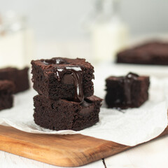 Brownies are stacked, showcasing a rich, gooey chocolate drizzle. The cozy kitchen atmosphere highlights a delightful dessert experience