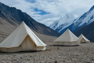 Three tents are set up in a field with mountains in the background. The tents are white and have a circular shape. The scene is peaceful and serene, with the mountains providing a beautiful backdrop