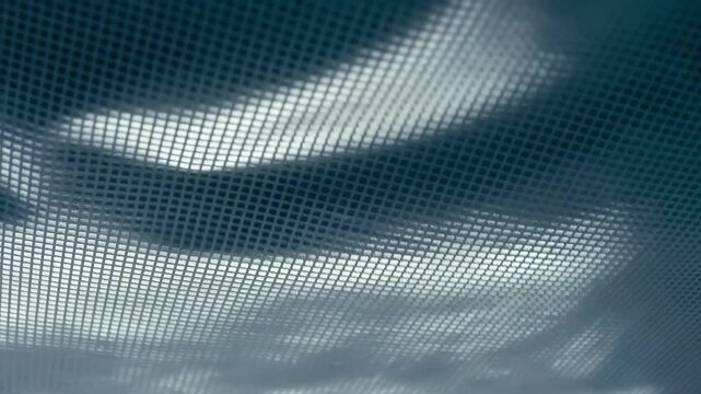 Fabric with a shiny checkered pattern flutters in the wind. Closeup. Macro