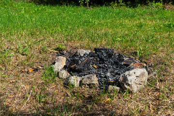 Obraz premium Campfire remnants in a grassy clearing during daylight hours