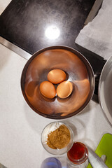 Three eggs in a steel utensil for cooking in a domestic kitchen ready to prepare