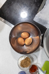 Three eggs in a steel utensil for cooking in a domestic kitchen ready to prepare
