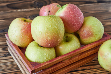 Fresh ripe apples in a wooden box on a rustic wooden table
