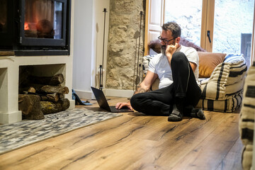 A 50-year-old man sits on the floor of his mountain chalet, peacefully relaxing and thinking deeply...
