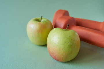 Apple and dumbbells on a green background. Healthy lifestyle concept.