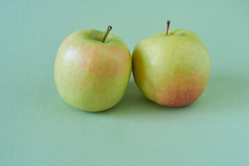 Two green apples on a green background, close-up, copy space