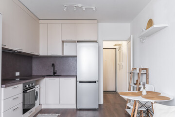 Modern built-in kitchen in minimalist style. kitchen unit with beige upper and lower cabinets....
