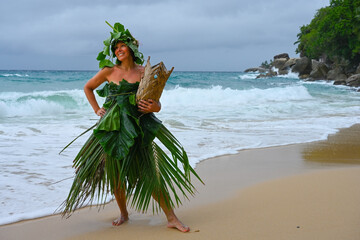 Robinson Crusoe woman dressed in palm branches on the seashore