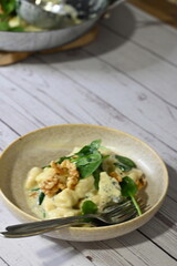 Close-up view of potato gnocchi served with a creamy blue cheese sauce and walnuts on a white plate. A rich and flavorful dish combining soft, pillowy gnocchi with the bold taste of blue cheese 