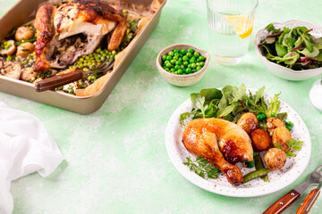 Baked chicken with baby potatoes and salad on a green background.