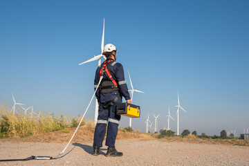 Engineer wearing uniform inspection and survey work in wind turbine farms rotation to generate...