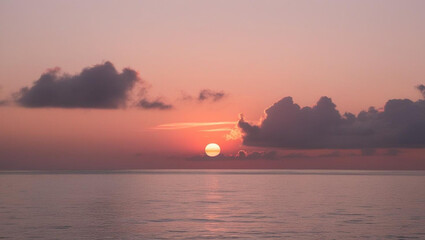 Fototapeta premium A serene sunset over the ocean with soft orange and pink hues in the sky