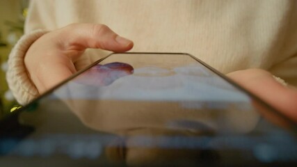 Young woman leisurely scrolling through social media news feed on smartphone while sitting comfortably near soft christmas lights with warm bokeh background - Powered by Adobe